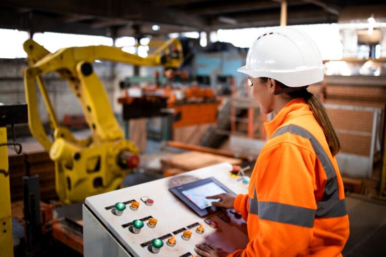 Woman operating robotic machinenery in a manufacturing warehouse using PowerHouse WMS.