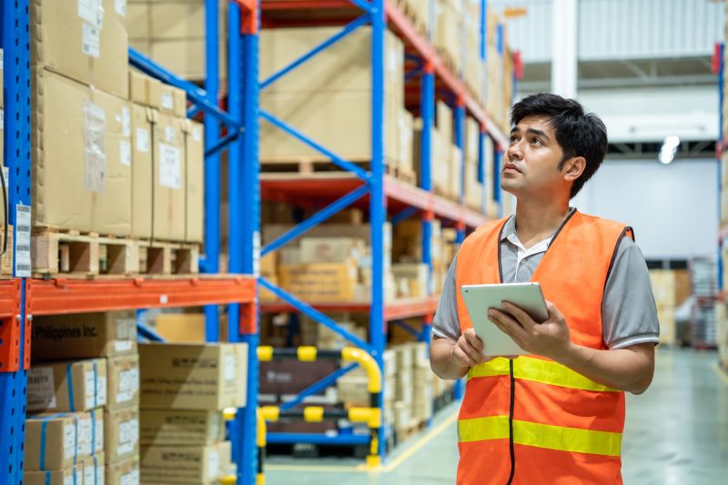 Warehouse manager performing cycle counting on inventory in a large warehouse.