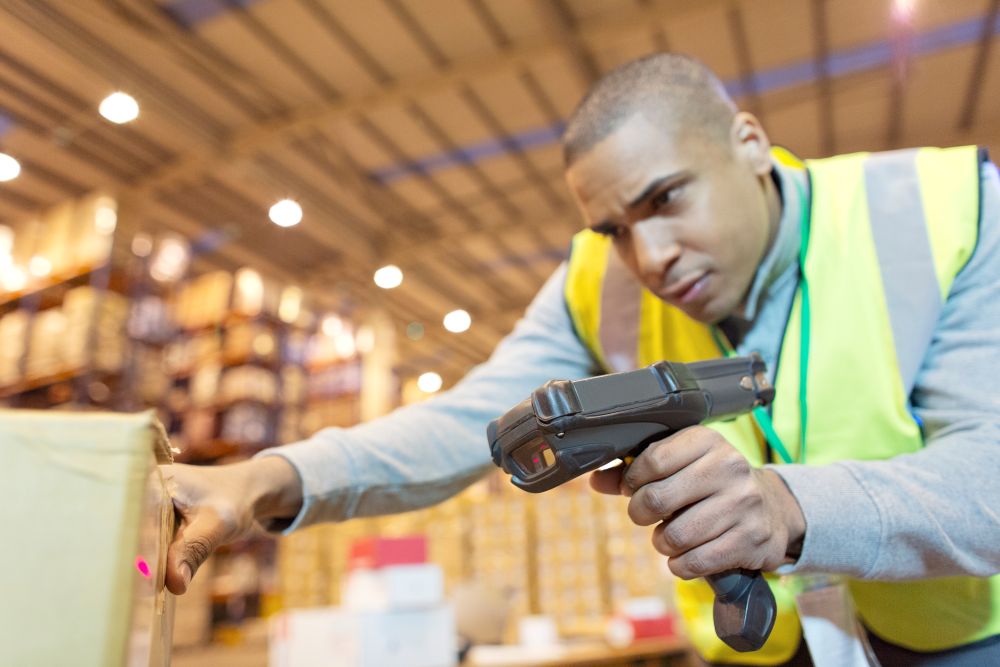Warehouse worker using an RF gut to scan a barcode for a barcode inventory system.